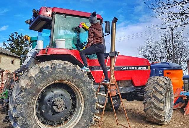 female farmer washing red tractor
